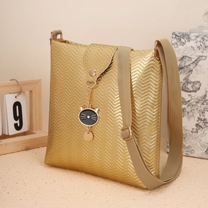 Détail du sac seau doré à motif ondulé avec charm en forme de tête de chat