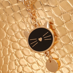Gros plan d'un sac à motif crocodile doré avec pendentif chat et chaîne en métal