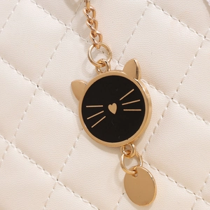 Détail du pendentif chat en métal doré avec incrustation noire sur sac en cuir matelassé