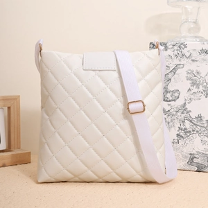 Détail d'un sac seau blanc matelassé avec finitions dorées et large bandoulière en tissu