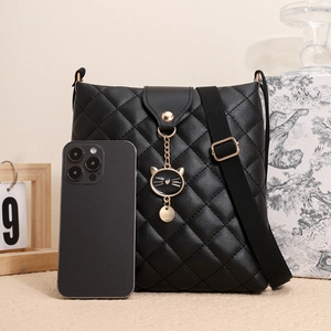 Détail du sac bandoulière noir matelassé avec breloque chat et bandoulière large avec téléphone