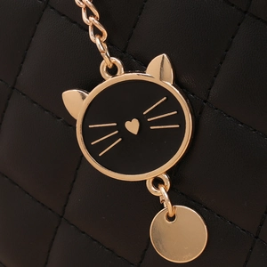 Vue détaillée du cuir noir matelassé et du pendentif doré en forme de chat sur le sac