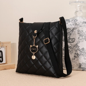 Détail du sac bandoulière matelassé noir avec pendentif chat en métal et sangle en tissu
