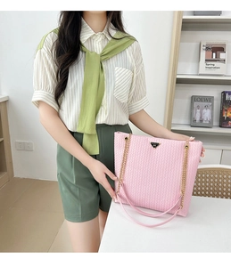 Detalle del bolso tote rosa tejido con correa de cadena dorada y placa de logotipo