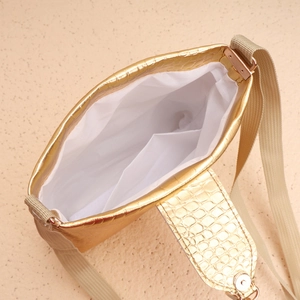 Détail du sac doré à texture crocodile avec fermoir magnétique et poche intérieure