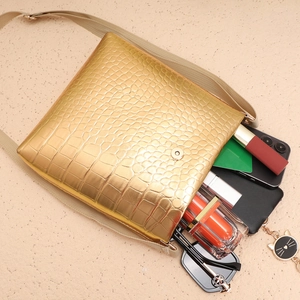 Vue du rangement interne du sac doré motif crocodile avec portable et maquillage