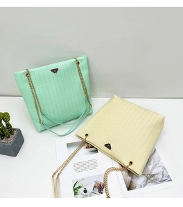 Detalle de textura tejida en bolsos tote verde menta y crema con cadena dorada