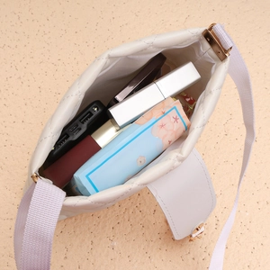 Vue intérieure montrant la grande capacité du sac seau matelassé blanc avec objets du quotidien