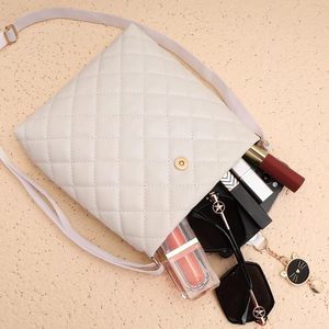 Détail d'un sac bandoulière matelassé blanc montrant l'espace pour lunettes et maquillage