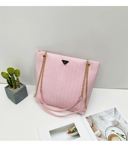 Detalle del bolso tote rosa trenzado con textura en V y correa de cadena dorada fina