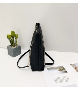 Primer plano del bolso tote trenzado negro con cadena dorada y textura lateral elegante