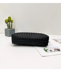 Detalle del bolso tote de cuero trenzado negro con textura gruesa en fondo blanco