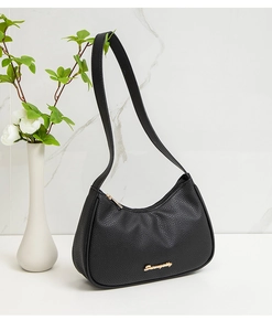 Close-up of black pebble leather underarm bag with gold logo and elegant home decor