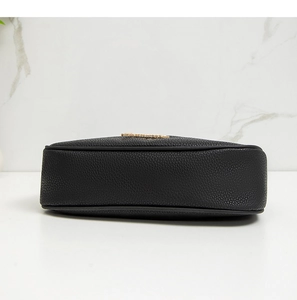 Close-up of black pebbled leather texture and golden metal logo on the shoulder bag