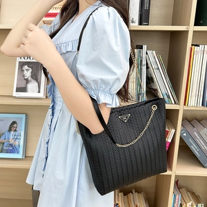 Bolso tote de moda en tejido vertical negro con cadena dorada llevado por una modelo