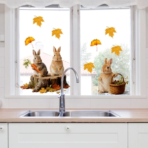 Detail view of cartoon bunny window stickers with autumn maple leaves on kitchen glass