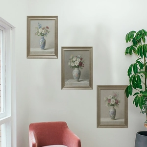 Detailed view of three self-adhesive framed wall stickers with floral art on a white wall