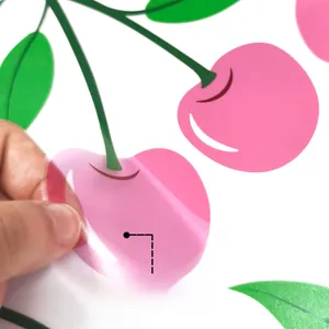 Detail showing hand peeling a pink cherry wall sticker with adhesive backing