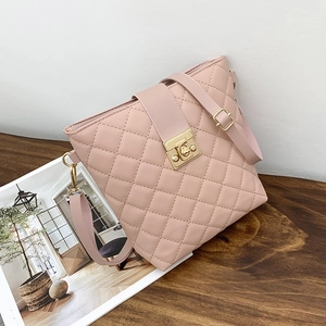 Sac seau matelassé rose avec fermoir doré et bandoulière sur un bureau en bois