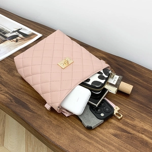 Sac seau matelassé rose avec fermoir doré sur table en bois montrant l'espace intérieur