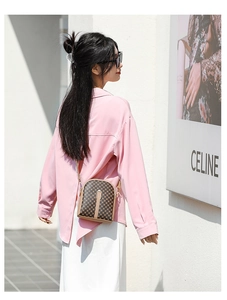 Outdoor shot of a brown checkered crossbody phone bag with gold metal hardware details