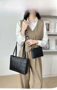Detail of black quilted tote bag and matching crossbody bag with patterned wide strap