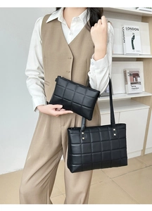 Detail of black quilted tote bag set with golden rivets and matching small clutch pouch