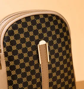Detailopname van de mini-tas met klaverprint en gouden ritssluiting