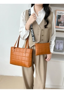 Close-up of brown quilted tote bag set with LOVE logo wide strap on a female model