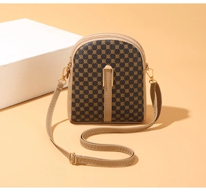 Detailed view of dark brown patterned phone bag with three zipper pockets and gold hardware