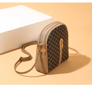 Detail of printed crossbody phone bag featuring multiple gold zippers and adjustable strap