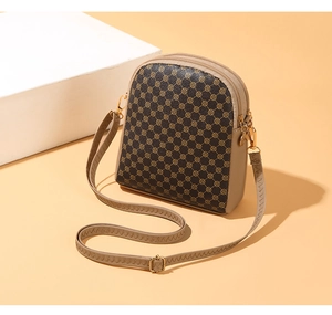 Detail view of khaki printed mini crossbody bag featuring three zipper compartments