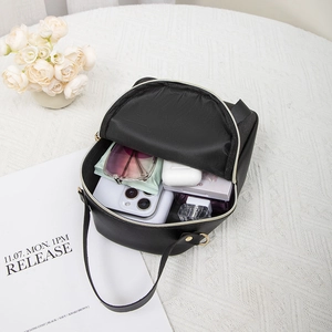 Mini black leather backpack with bow print and gold zippers showing interior storage capacity