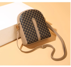 Detail of vintage patterned crossbody phone bag with dual zippers and gold-tone hardware