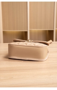 Detailansicht der beigen Stepptasche mit Bodenstruktur und goldenem Verschluss