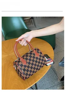 Close-up of checkerboard Boston handbag with vintage letter print and leather handle