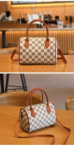 Detail of Boston bag with checkered letter pattern and brown pebbled leather handles