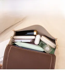 Vue intérieure montrant la grande capacité du sac à bandoulière carré avec objets quotidiens