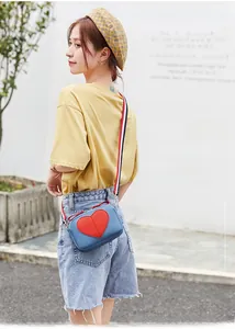 Blue lychee pattern square bag with red heart detail and striped strap on model
