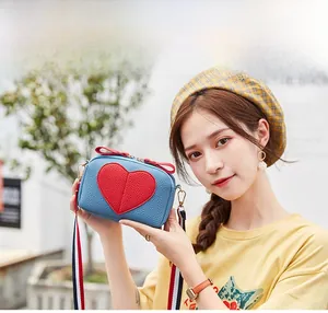 Blue lychee leather crossbody bag with red heart and striped strap on female model