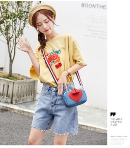 Blue lychee leather mini crossbody bag with red heart and striped strap on model
