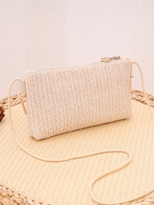 Detailed view of the woven raffia texture and golden metal zipper on the beige crossbody bag