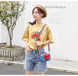 Blue crossbody bag with red heart patch and tri-color strap shown on model