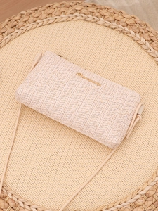 Detailed view of the woven herringbone texture and gold logo on the beige straw bag