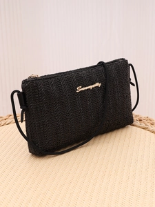 Detailed view of black woven texture bag with gold zipper and metal brand logo