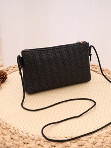 Macro detail of V-shaped woven texture on black straw crossbody bag with zipper