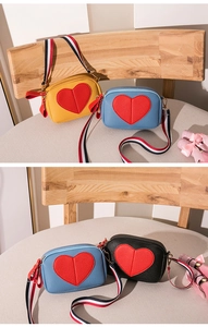 Close-up of heart-patterned leather mini bags with colorful striped woven shoulder straps