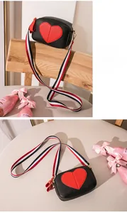 Detail of lychee leather crossbody bag with red heart and striped webbing strap