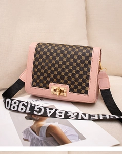 Détail du rabat à motifs vintage et du fermoir doré sur le sac à bandoulière rose