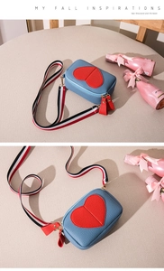 Close-up of blue lychee leather crossbody bag with heart detail and striped strap